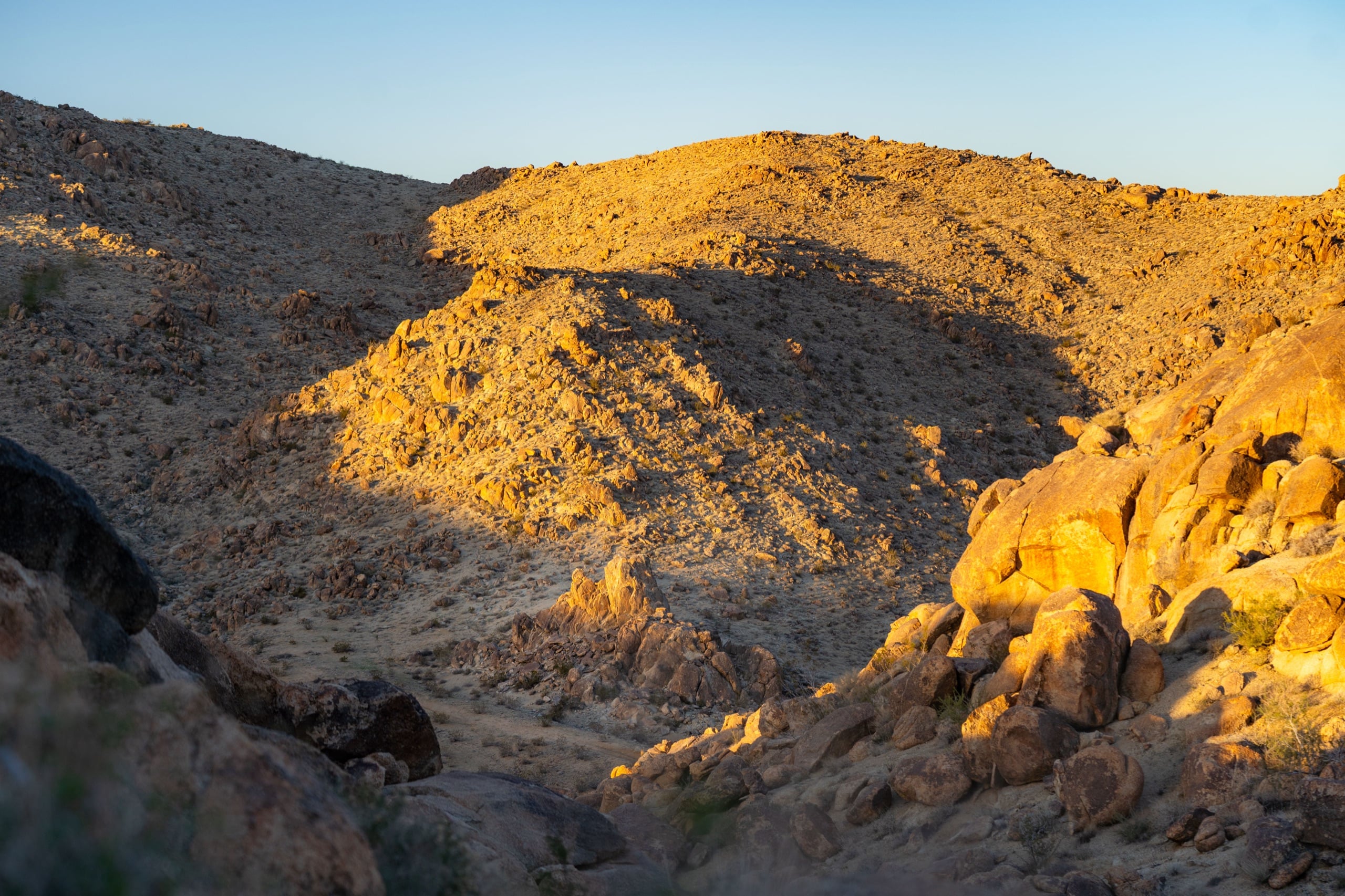 A dry canyon of tumbled boulders lit by the last golden light of day