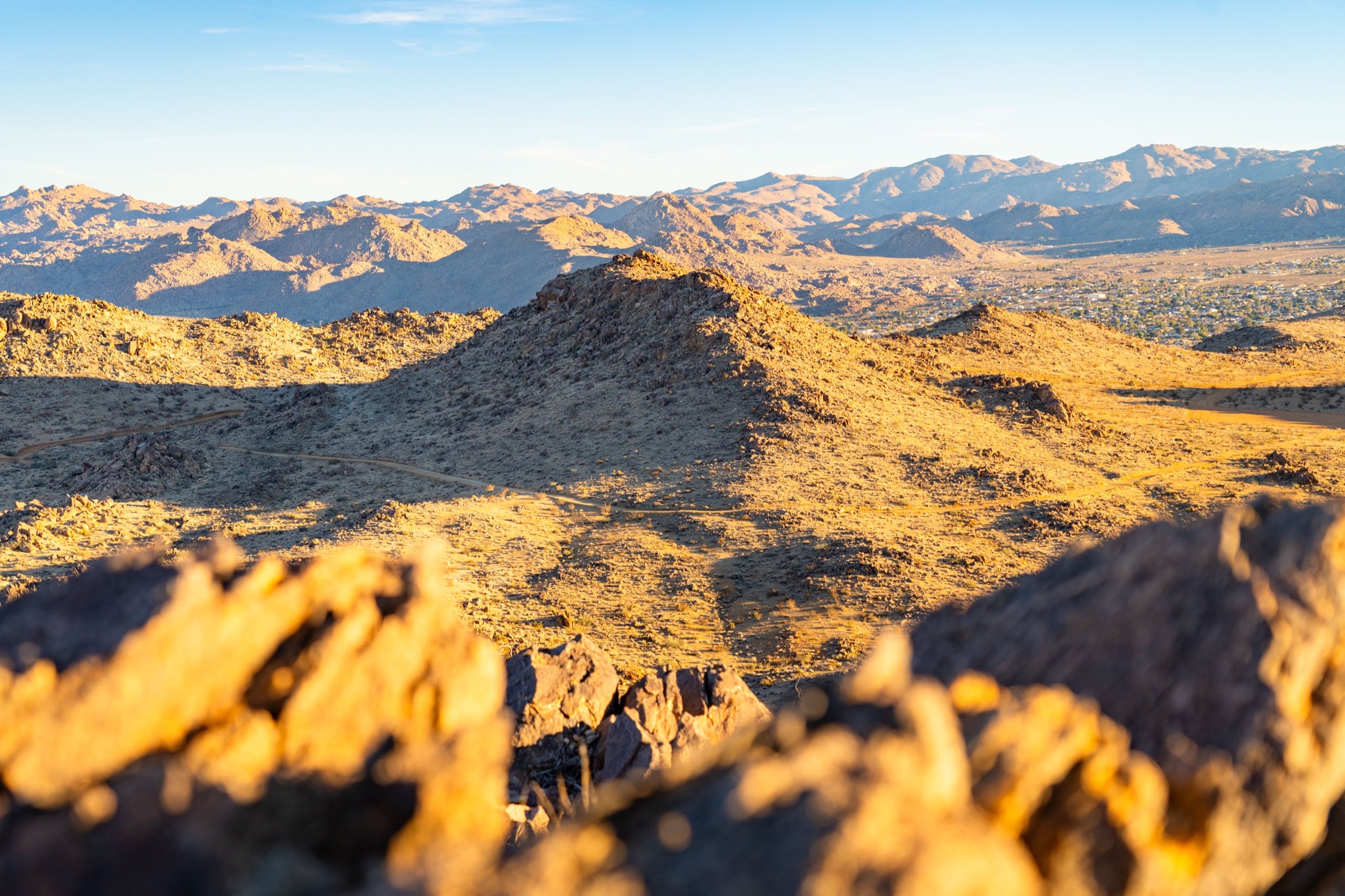A wide desert panorama from a rocky ridge, mountains dissolving into the distance