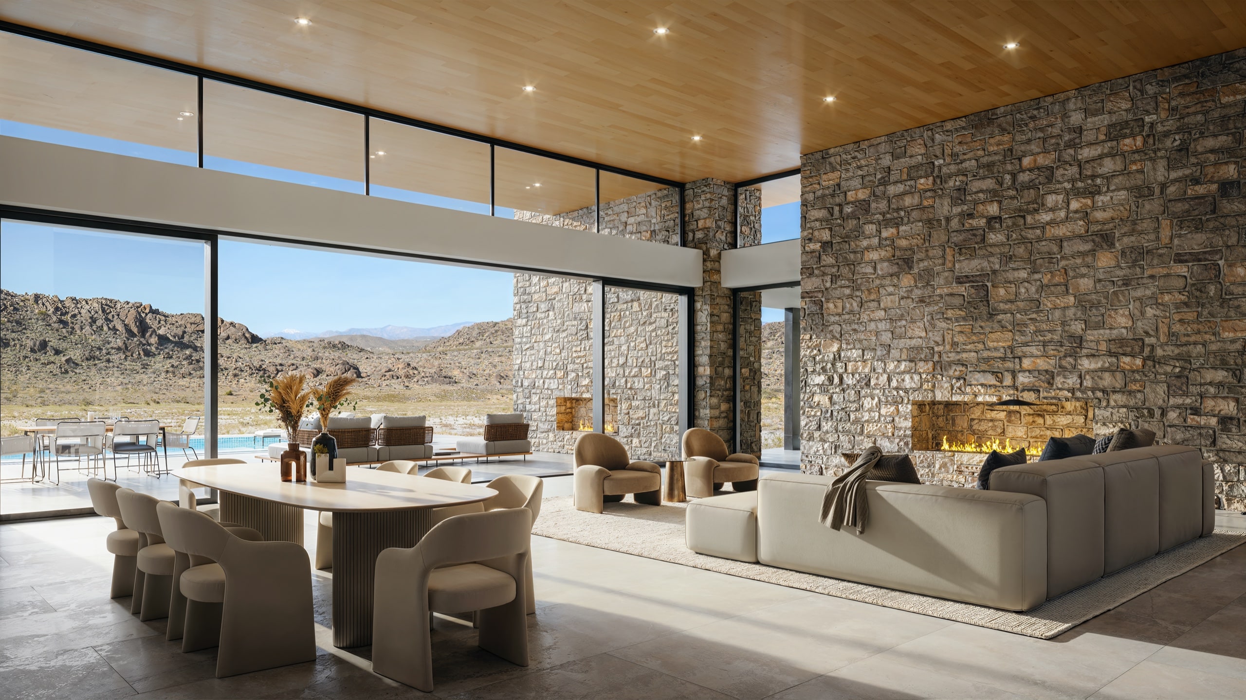 Rendering of a modern great room with stone fireplace wall, floor-to-ceiling windows opening to a pool and desert view
